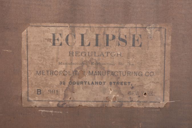 Ansonia Clock Co., New York, for Metropolitan Manufacturing Co., "Eclipse" hanging gingerbread clock, 8 day, time and simple calendar, spring driven movement in an oak case.