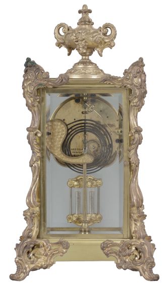 Ansonia Clock Co., New York, "Marchioness" crystal regulator with a spring driven 8 day time and half hour strike (rack and snail) movement (visible escapement) in a polished brass case with rich gold ornaments.