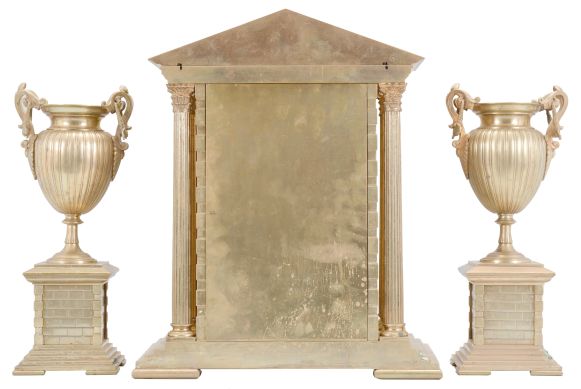 France, three piece mantel garniture set, 8 day, time and strike, spring driven pendule de Paris movement in a metal case of classic architectural form with stepped base, six full Corinthian columns flanking an ashlar facade with central arch, a painted ceramic panel within displaying a gilt chapter ring with Roman numerals, a scene of royals walking amidst an ancient city below the dial, all topped by a pediment with applied gilt ornament, two matching urns, both with painted ceramic panels.