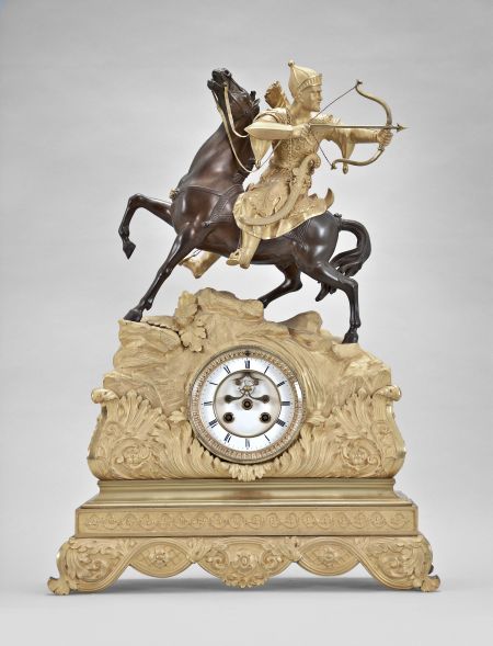 France, a gilt and patinated bronze figural mantel clock, the case replete with symmetrically arranged acanthus and other naturalistic top, the top with a rocky landscape and a Turkish archer wearing armor, astride a reddish brown patinated horse, the horse with head and one leg raised, the figure looking backward, his bowstring taut, and ready to release an arrow, Roman numeral white enamel dial with open escapement, 8 day, two train pendule de Paris movement