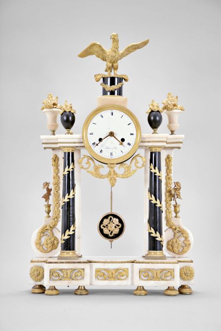 Dupas, a Paris, a late 18th century marble and gilt bronze mantel clock, the base on eight decorated feet, and with inset, scrolling foliate mounts, columns and pilasters supporting a stepped entablature with gilt bead molding, the columns in black marble with gilt capitals and bases, encircled with a spiral, leafy vine, the white pilasters with flanking, scroll buttress bases, mounted with a hanging garland, scrolling at the bottom, and terminating in a floral roundel, the clock case with scrolling foliate pendant, flanked by four urns with gilt flowers, and surmounted by an eagle with outstretched wings, and resting on a black pedestal with gilt festoon, roman numeral white enamel dial signed "Dupas a Paris", fancy gilt hands, 8- 15 day pendule de Paris movement with recoil escapement, silk thread suspension, and count wheel striking