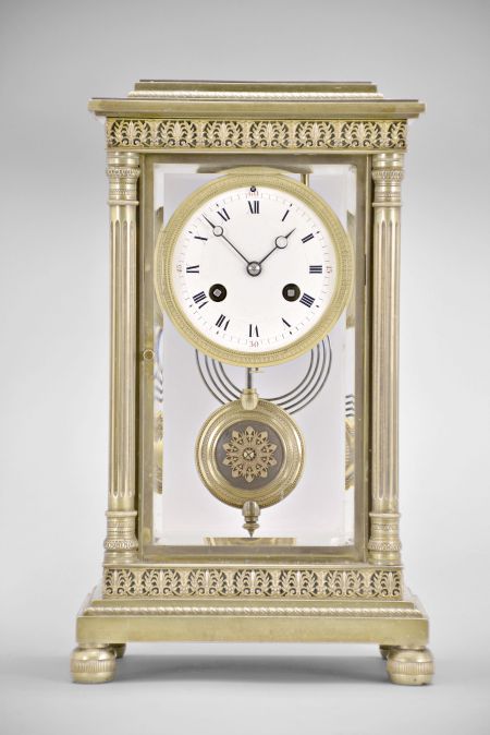 Vincenti & Cie, Paris, France, crystal regulator, 8 day, time and strike, spring driven pendule de Paris movement in a glazed brass case on cast bun feet supporting fluted columns on the front corners and pilasters on the back corners, stepped and molded base and top with repeating palmette and laurel fretwork, matching pendulum, Roman numeral white enamel dial with red Arabic numerals at the quarters, and blued steel Breguet style hands.