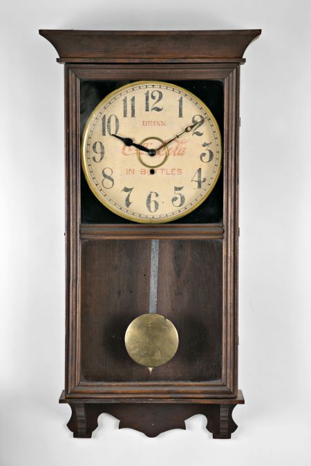 William L. Gilbert Clock Co., Winsted, Conn., "University" wall hanging store regulator with a spring driven 8 day timepiece movement with a 12" Coca Cola advertising dial in a wooden case with a polished mahogany finish.