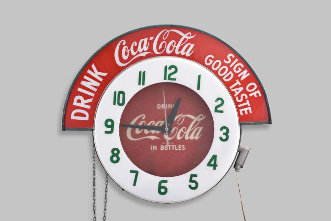 Clocks- 2 (Two) Coca Cola electric backlit advertising clocks: (1) Large period sign advertising "DRINK Coca Cola SIGN OF GOOD TASTE" with 24.5" plastic dial reading "DRINK IN BOTTLES "; (2) Small reproduction in 50