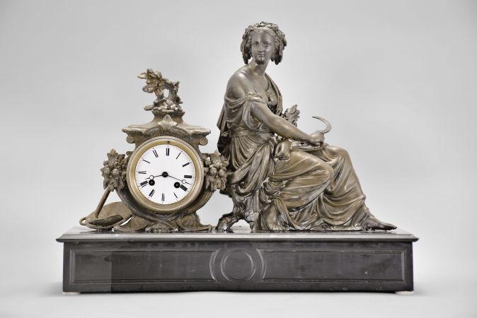 Japy Frères & Cie, Paris, France, figural mantel clock, 8 day, time and strike, spring driven pendule de Paris movement, black slate base with molded front and top supporting a cast spelter case with agrarian theme including a basket and hoe, and seated female figure with a sickle in one hand and a sheaf of wheat in the other, white enamel dial with Roman numerals, and blued steel Breguet hands.