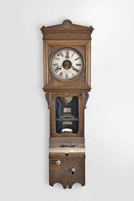 International Time Recording Co., Endicott, NY sold by James & Co., Rochester N.Y., wall hanging punch clock, 8 day, time and day of the week, spring driven movement in an oak case with punch mechanism and painted metal dial with exposed center and day of the week aperture