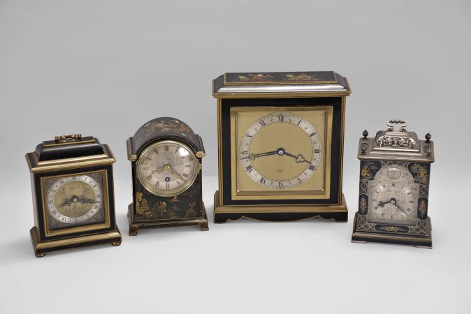 Clocks- 4 (Four) Japanned desk clocks, 8 day, time only, spring driven movements: (1) Elliott, London, desk clock with a square case with molded top and base; (2) Elliott, London, miniature bracket clock, black case with gold trim; (3) Samuel Marti for J.E. Caldwell, Philadelphia, miniature bracket clock with guilloché silvered dial. (4) Canham, London, miniature bracket clock with engraved silvered dial.