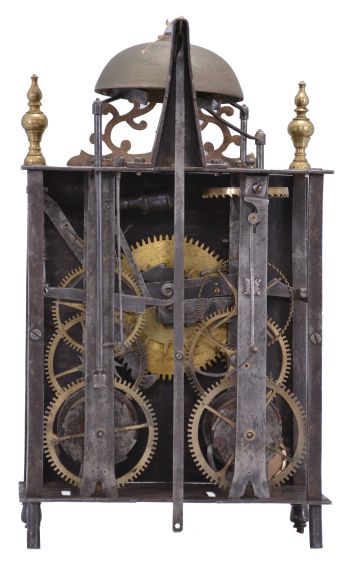 France, Comtoise lantern clock, 8 day, time and strike with alarm, weight driven movement with verge escapement, thread suspension with rear-hanging pendulum in a posted iron frame case, heavy brass chapter ring with Roman numerals, single brass hand, alarm ring with Roman numerals, applied brass spandrels with hearts, all resting on turned iron feet in the front, and topped with a thick pierced brass fronton flanked by two turned brass finials.