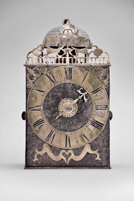 France, Comtoise clock, 8 day, time and strike with alarm, weight driven movement with verge escapement, thread suspension with rear-hanging pendulum in a iron post and plate frame, brass chapter ring with engraved Roman numerals, alarm dial with Arabic numerals, single brass hand, applied brass spandrels and pivoted winding arbor shutters, topped by flat pierced brass fronton with trademark.