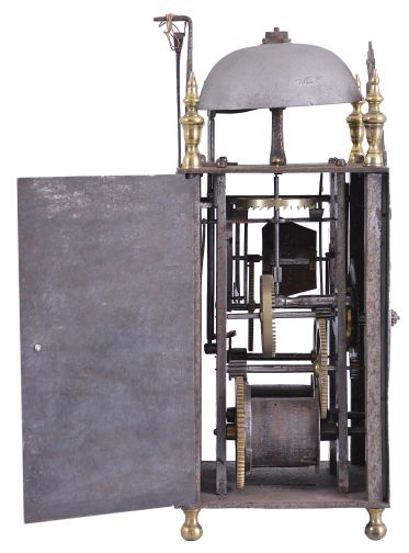 France, Comtoise lantern clock, 8 day, time and strike, weight driven movement with verge escapement, thread suspension with rear-hanging pendulum in a iron post and plate frame, pewter chapter ring with engraved Roman numerals, single brass hand, applied brass fleur de lis spandrels and pivoted winding arbor shutters, all resting on four turned brass feet, and topped by flat pierced brass fronton flanked by four turned brass finials.