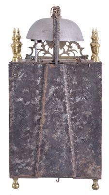 France, Comtoise lantern clock, 8 day, time and strike, weight driven movement with verge escapement, thread suspension with rear-hanging pendulum in a iron post and plate frame, pewter chapter ring with engraved Roman numerals, single brass hand, applied brass fleur de lis spandrels and pivoted winding arbor shutters, all resting on four turned brass feet, and topped by flat pierced brass fronton flanked by four turned brass finials.