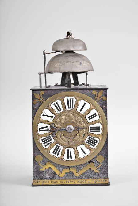 France, Comtoise clock, 8 day, time and strike with alarm, weight driven movement with verge escapement, thread suspension with rear-hanging pendulum in a iron post and plate frame, cast brass dial with a profile of Prince Louis, Dauphin of France surrounded by laurels and fleur de lis, inset white enamel cartouches with Roman numerals, single pierced iron hand, applied brass fleur de lis spandrels above the dial and pivoted winding arbor shutters below, and brass plaque stamped with the words "FAIT POUR JEAN BAPTISTE RIPOZ A COMARET ".