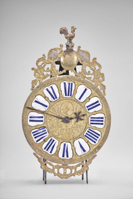 France, Comtoise lantern clock, 30 hour, time and strike, weight driven movement with rare pin wheel escapement, iron frame and feet, rear mounted thread suspension, cast brass dial with profile of Louis XV and inset with 12 white enamel cartouches with Roman numerals, outer ring with Arabic numerals every 5 minutes, cast bronze fronton with trumpeters flanking a medallion topped by the Gallic rooster, two iron hands.