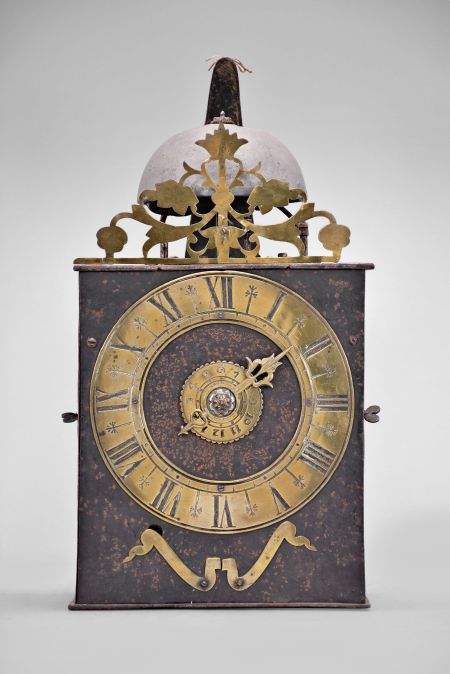 France, Comtoise clock, 8 day, time and strike with alarm, weight driven movement with verge escapement, thread suspension with rear-hanging pendulum in a iron post and plate frame, brass chapter ring with Roman numerals, brass alarm ring with Arabic numerals, pivoted winding arbor shutters, single pierced brass hand, all surmounted by a pierced brass fronton.