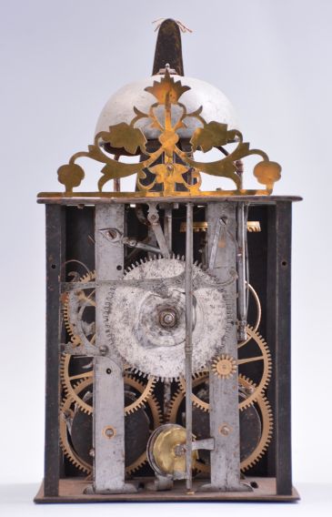 France, Comtoise clock, 8 day, time and strike with alarm, weight driven movement with verge escapement, thread suspension with rear-hanging pendulum in a iron post and plate frame, brass chapter ring with Roman numerals, brass alarm ring with Arabic numerals, pivoted winding arbor shutters, single pierced brass hand, all surmounted by a pierced brass fronton.