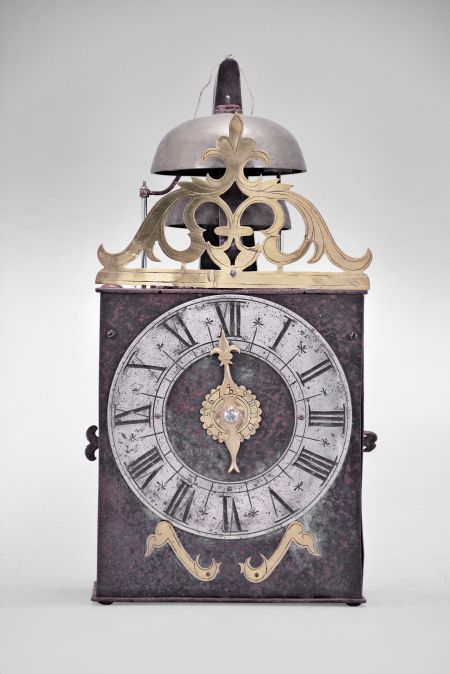 France, Comtoise clock, 8 day, time and strike with alarm, weight driven movement with verge escapement, thread suspension with rear-hanging pendulum in a iron post and plate frame, pewter chapter ring with engraved Roman numerals, brass alarm ring with Arabic numerals, pivoted brass winding arbor shutters with engraving, pierced brass fronton with engraving, and single brass fleur de lis hand.