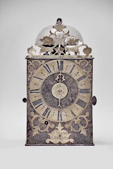 J. Mayet, Morbier, France, Comtoise clock, 8 day, time and alarm, weight driven movement with verge escapement, thread suspension with rear-hanging pendulum in a iron post and plate frame, brass chapter ring with engraved Roman numerals, brass alarm ring with engraved Arabic numerals, pierced brass spandrels and engraved plaque below the dial reading "J. Mayet a Morbier", single brass hand, all topped with a pierced brass fronton.