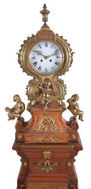 Marti & Cie, Paris, France, figural shelf clock, 8 day, time and strike, spring driven movement with white enamel dial in a highly stylized cast brass case set on veneered wooden base surmounted by three putti grasping bacchanal themed items and cast brass appliqués including matching stand with cast brass appliqués, veneers and ornaments.