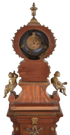 Marti & Cie, Paris, France, figural shelf clock, 8 day, time and strike, spring driven movement with white enamel dial in a highly stylized cast brass case set on veneered wooden base surmounted by three putti grasping bacchanal themed items and cast brass appliqués including matching stand with cast brass appliqués, veneers and ornaments.