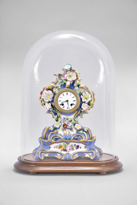 France, two-part porcelain mantel clock, 8 day, time and strike, pendule de Paris movement with silk thread suspension, the case in the style of Jacob Petit, decorated with molded and brightly painted naturalistic ornament, blue ground highlighted by bright gilding, white enamel dial with Roman numerals, Breguet style steel hands, all resting on a wood base under a glass dome