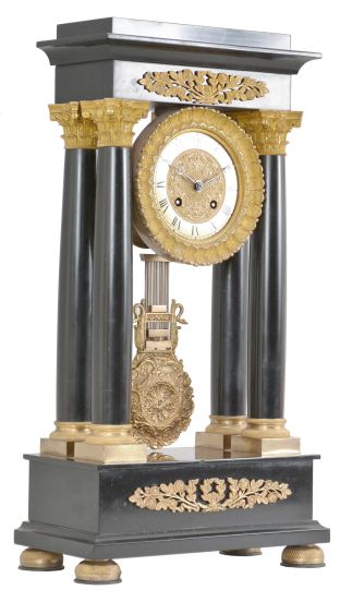 France, Empire portico clock, 8 day, time and strike, spring driven pendule de Paris movement in a polished black slate case on cast brass feet, the base and top with applied gilt rose ornaments, four Corinthian columns with gilt bases and capitals, the gilt bezel with repeating acanthus leaf design, gilt chapter ring with Roman numerals, cast dial center and gridiron pendulum both with floral designs, blued steel Breguet hands.