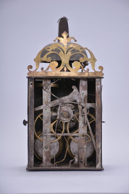 France, Comtoise clock, 8 day, time and strike with alarm, weight driven movement with verge escapement, thread suspension with rear-hanging pendulum in a iron post and plate frame, brass chapter ring with engraved Roman numerals, brass alarm ring with engraved Arabic numerals, pivoted winding arbor shutters, single pierced brass hand, the top with pierced brass fronton.